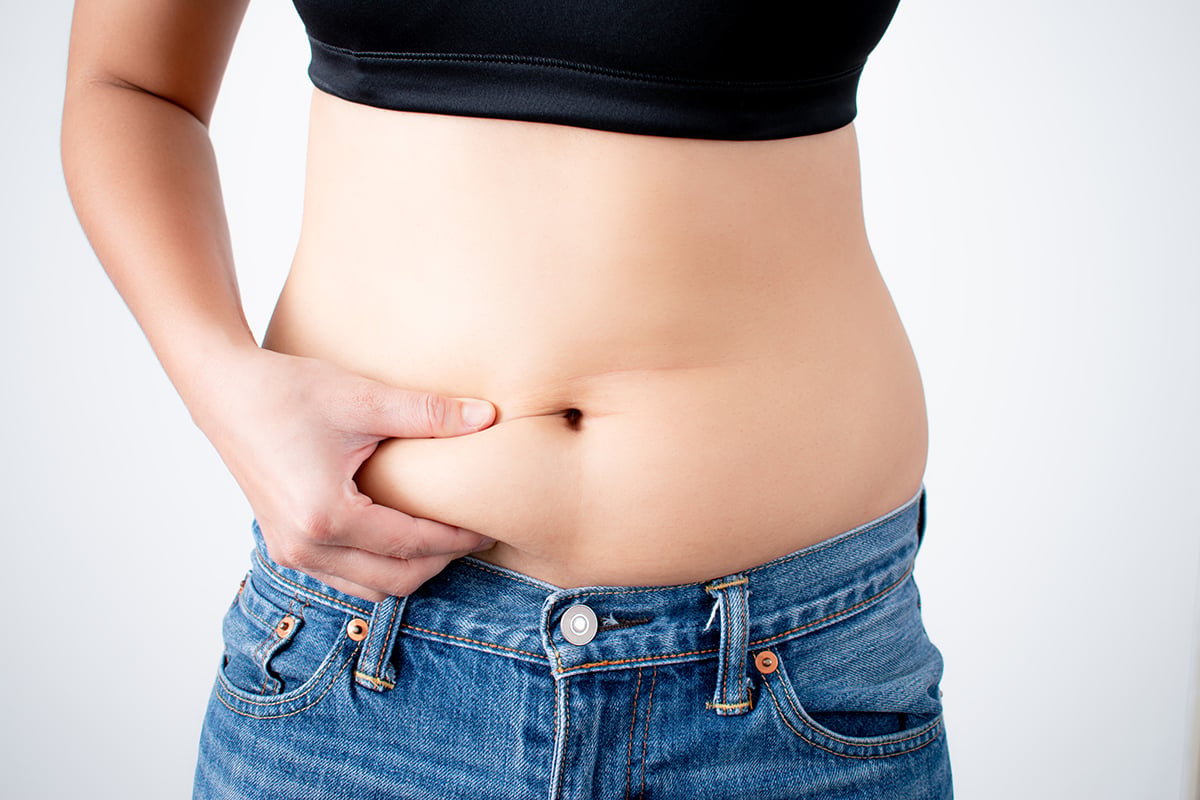 a close up of a womans hand that grabs belly fat a close up of a womans hand that grabs belly fat