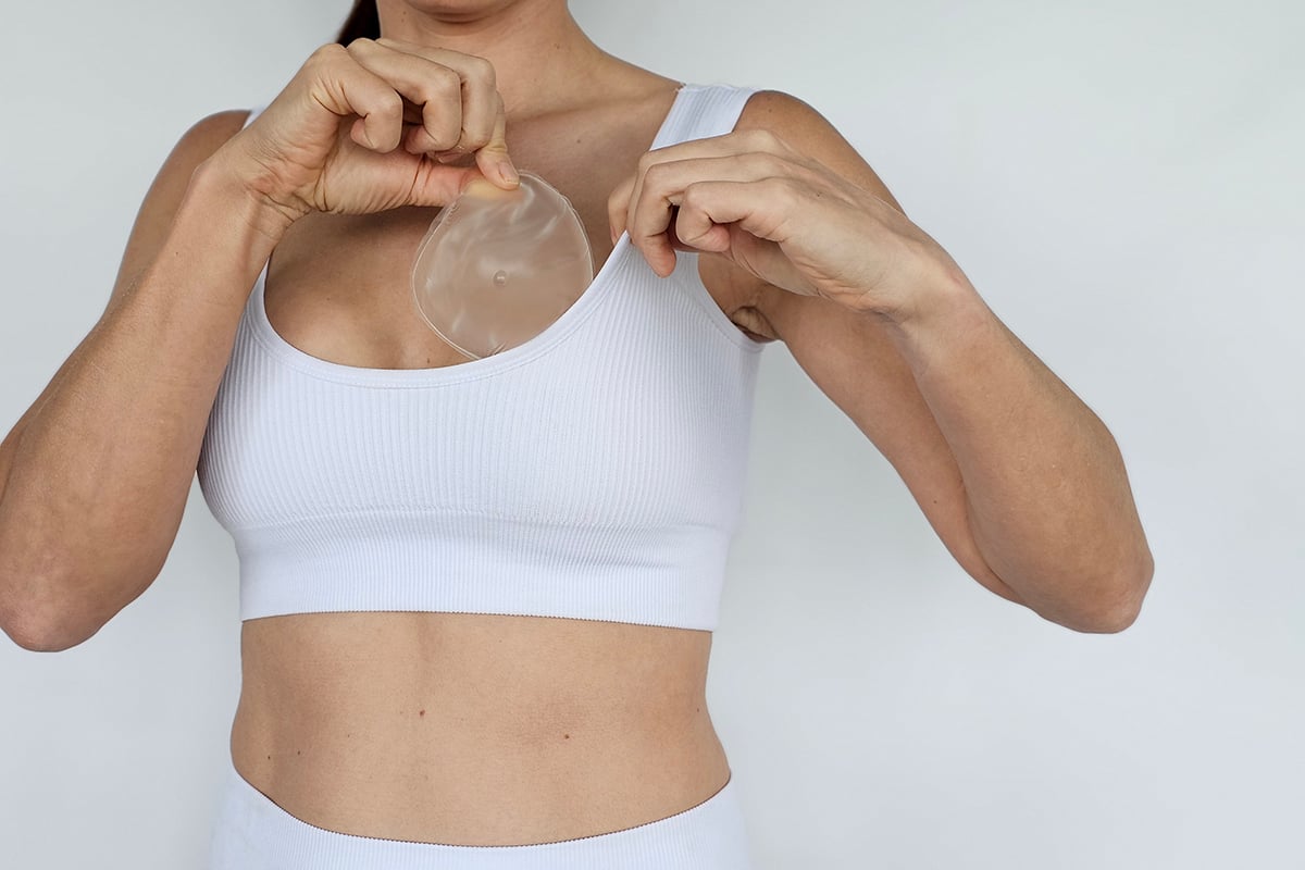 a woman demonstrates the process of breast augmentation using a silicone implant