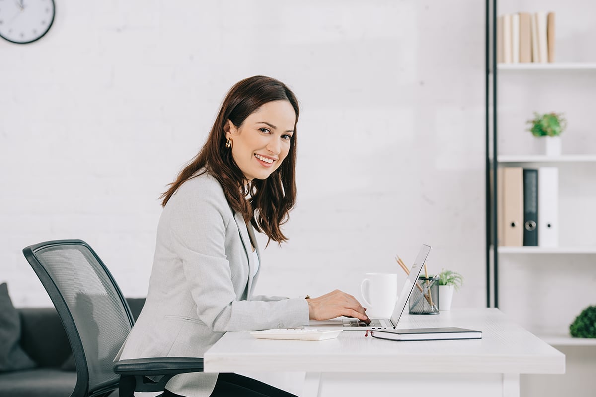 smiling secretary looking at camera while sitting at workplace in office smiling secretary looking at camera while sitting at workplace in office