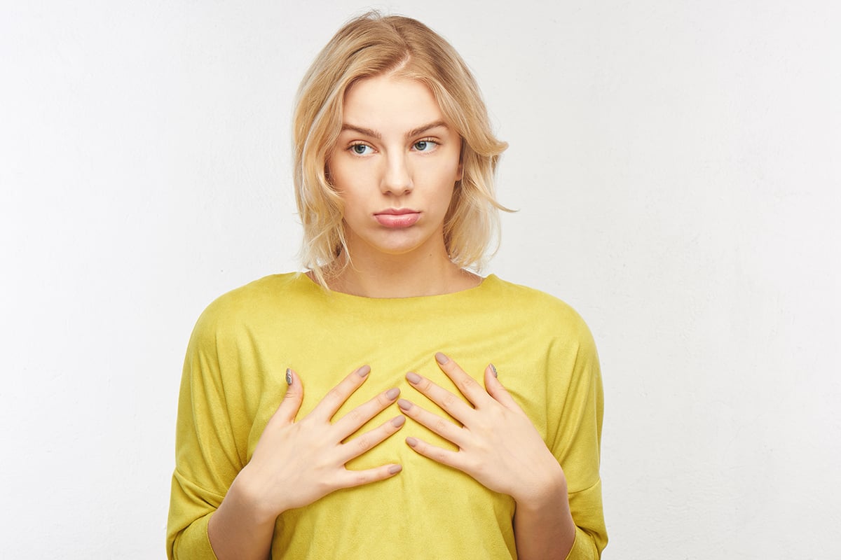 upset young woman with a displeased facial expression touches her tiny tits upset young woman with a displeased facial expression touches her tiny tits
