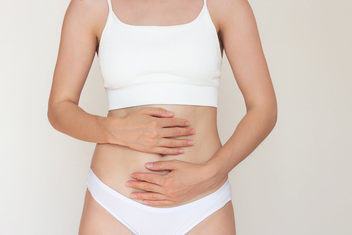 woman wearing white underwear holding her stomach with both hands woman wearing white underwear holding her stomach with both hands