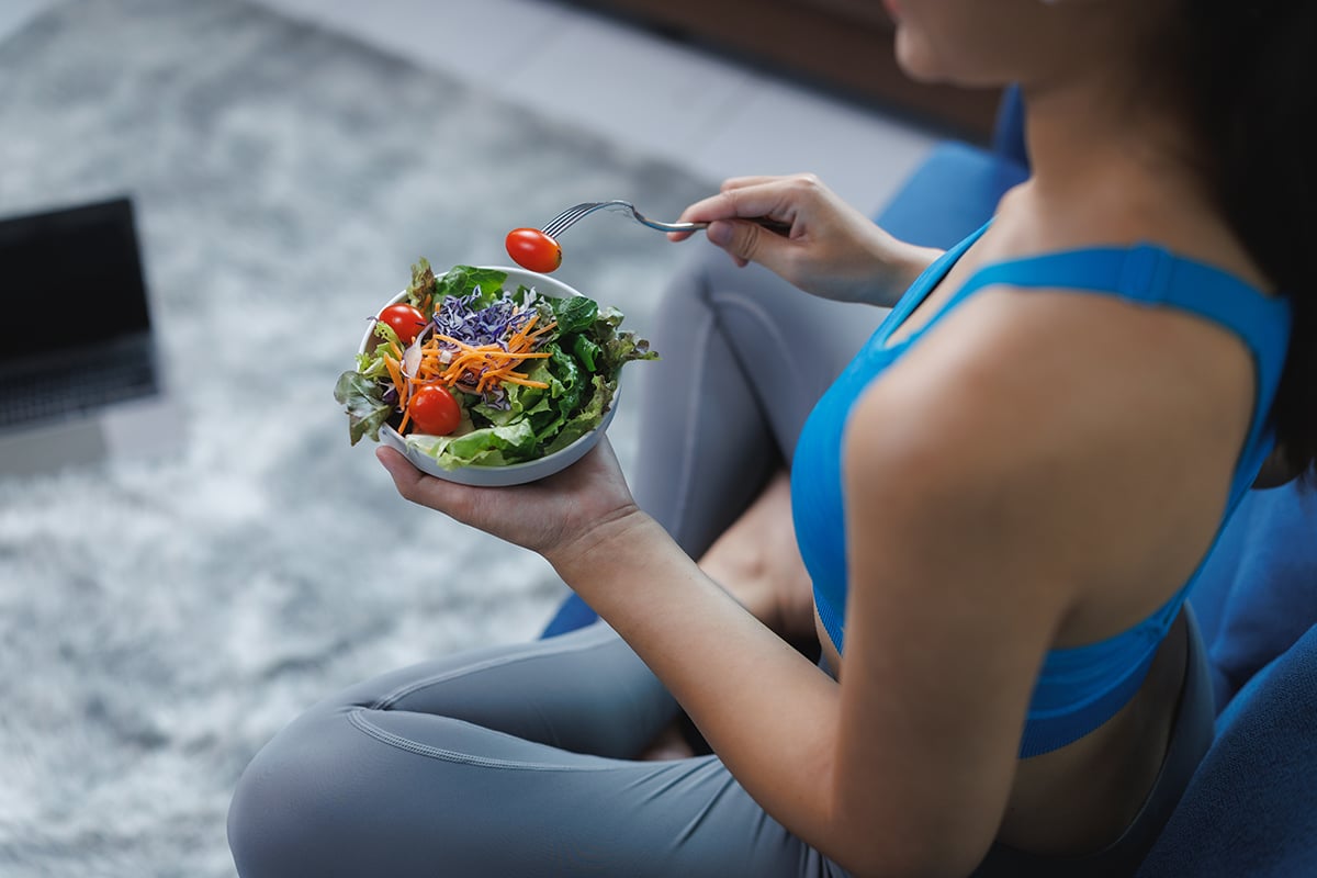 young woman eating healthy salad after workout at home young woman eating healthy salad after workout at home