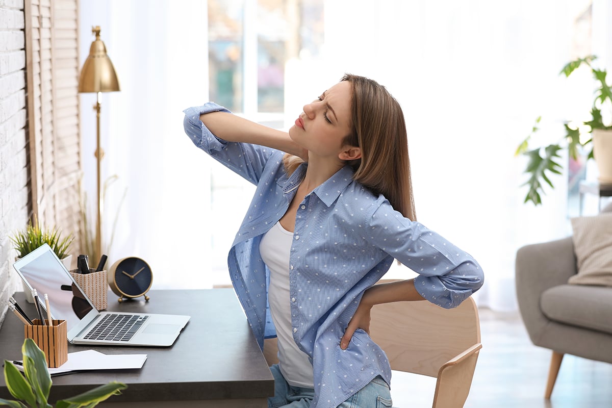 young woman suffering from back pain in office young woman suffering from back pain in office